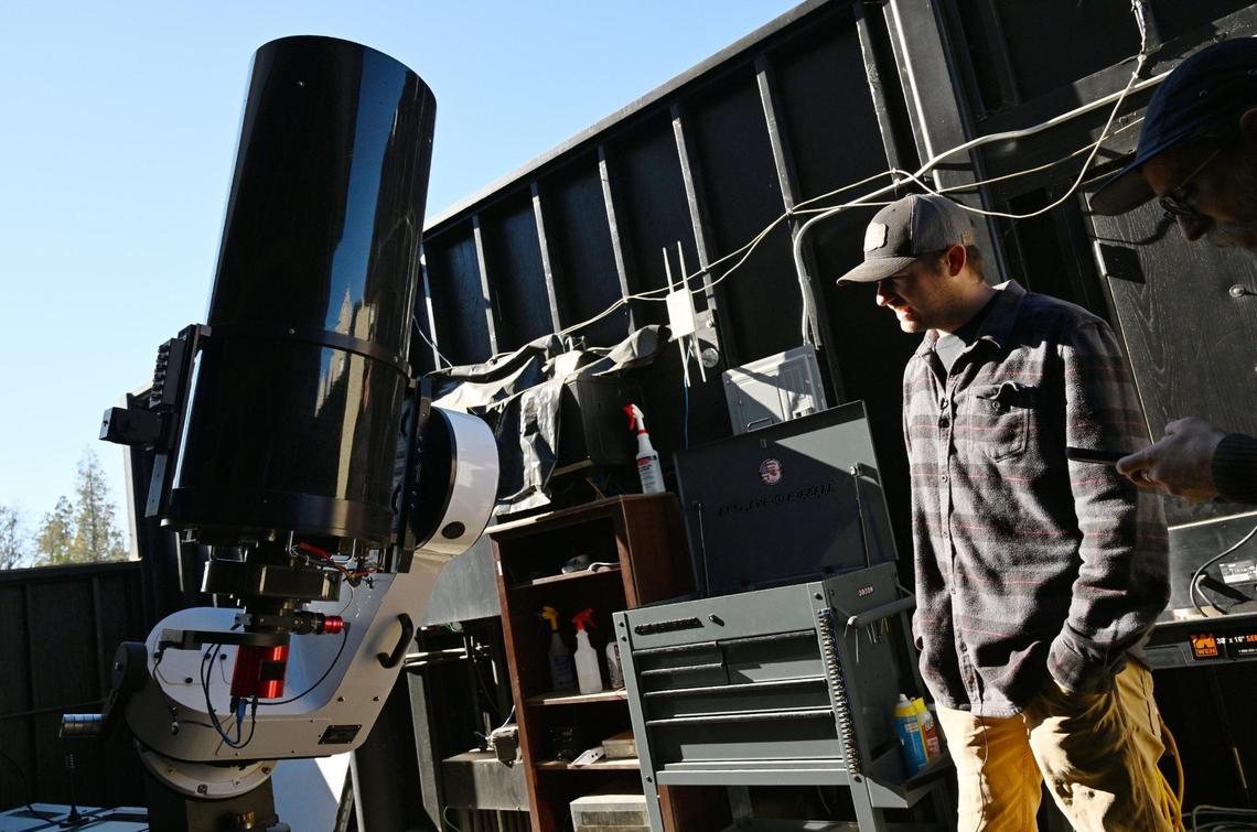 With the roll-off roof structure open and revealing the sky, Sierra Remote Observatory technician Sam Miller stands next to a telescope Tuesday, Jan. 21, 2025 near Auberry.