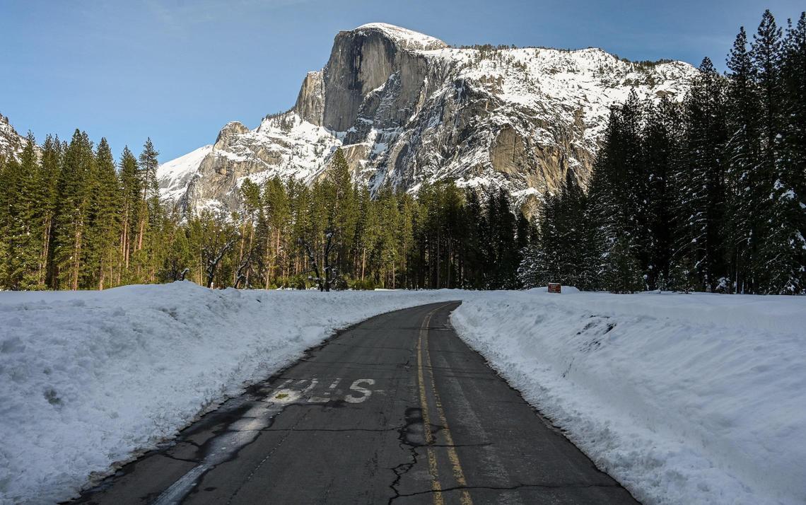 Half Dome comes into view from Southside Drive near Curry Village in Yosemite Valley on Friday, March 3, 2023. The roadway banks are piled high with snow from passing snowplows.