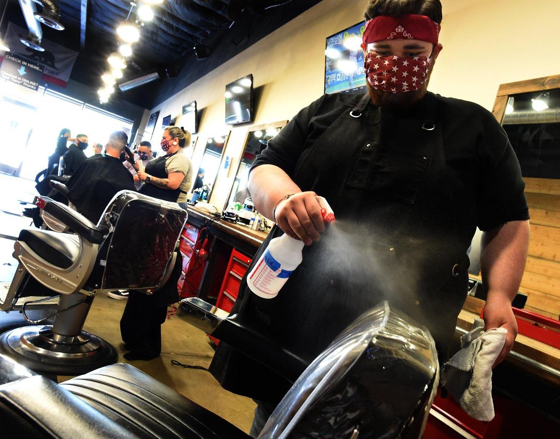Rafael Ramos sanitizes a barber chair at the Great American Barbershop in Clovis, Wednesday May 27, 2020.
