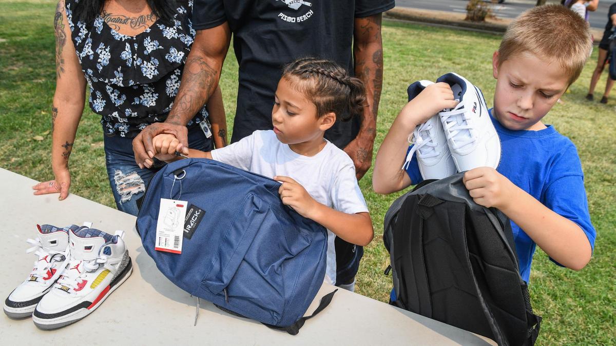 Brothers Jeffrey Batten, right, 11, and Edward Harding, 7, both of Fresno pack their new shoes into new backpacks at Cary Park in Fresno during the Community Kick it Outreach shoe giveaway on Saturday, Aug. 7, 2021. This is the fourth annual she giveaway organized by Pastor Edward Thomas of Living World International Church in Fresno to provide footwear for families in need before the start of the school year. Donated backpacks and school supplies were also giving out.