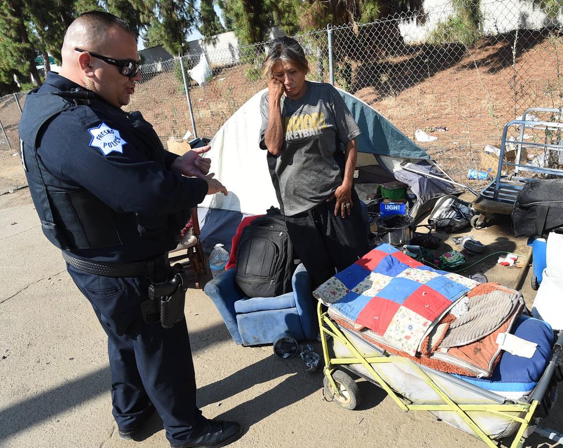 Elena Zurala listens as Fresno Police Officer Albert Avelar advises her on what she can take with her during a cleanup of an alley near Highway 41 on Wednesday morning, Aug. 14, 2018. She was offered assistance and declined it.