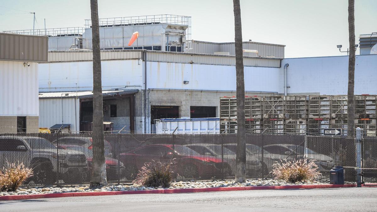 Buildings stand beyond chicken cages and dumpster bins at the Foster Farms Cherry Avenue facility in Fresno on Wednesday, May 26, 2021.