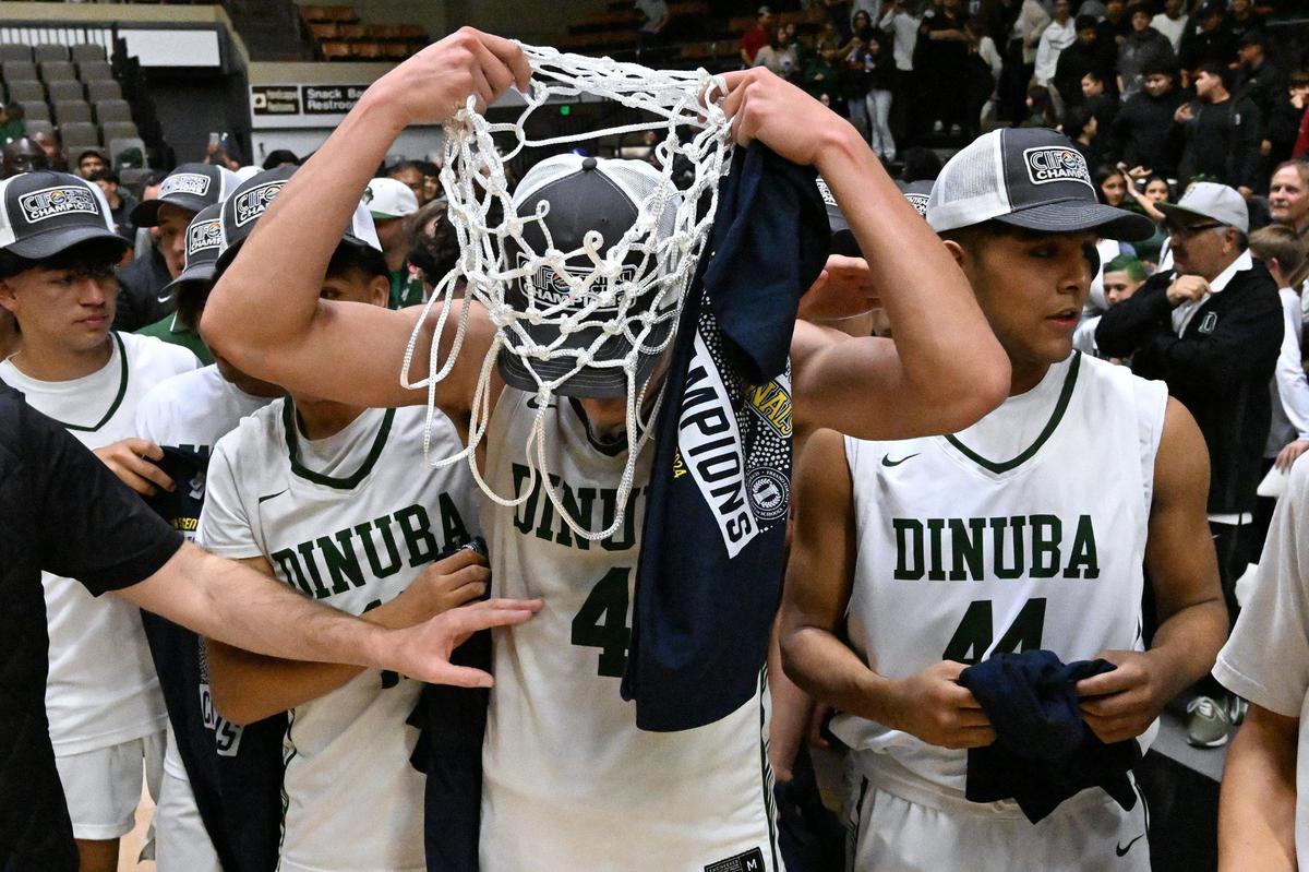 Dinuba’s Javier Torres, center, drapes the net around his neck as Dinuba celebrates its 46-42 win against Mission Prep in the Division II game Friday, Feb. 23, 2024 in Fresno.