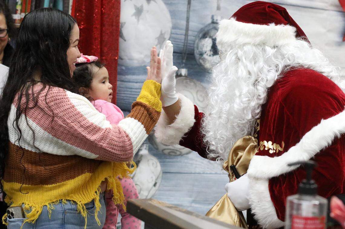 Isela Molina saluda a Santa Clos durante el evento de Navidad de la Familia Migrante 2023 que se llevó a cabo en la biblioteca de la Firebaugh High School el 13 de diciembre.