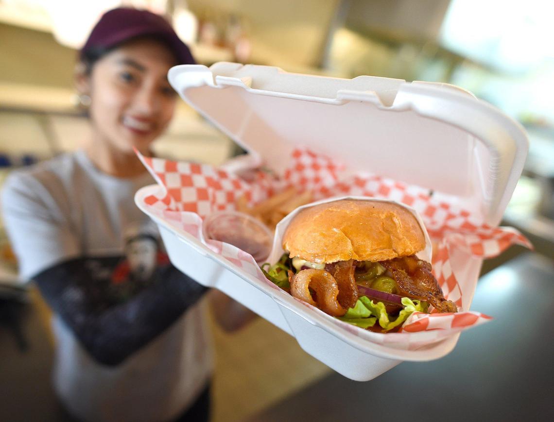 Take 3 cook Connie Rodriguez shows a loaded double burger served up for delivery for essential workers during the COVID-19 crisis, paid for by donations from the public.