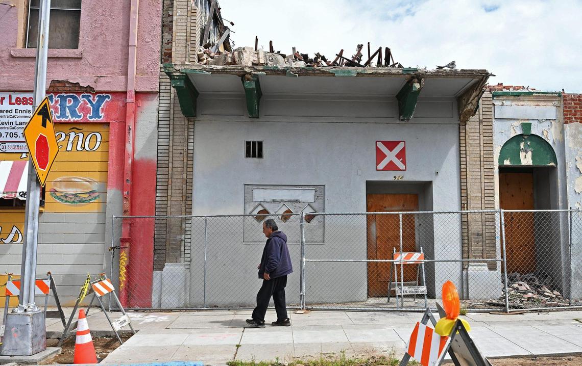 A man passes the front as demolition continues in the rear at the Bow On Tong Association building, part of the City of Fresno’s restoration plan in Chinatown, shown Tuesday, April 1, 2025 in Fresno.