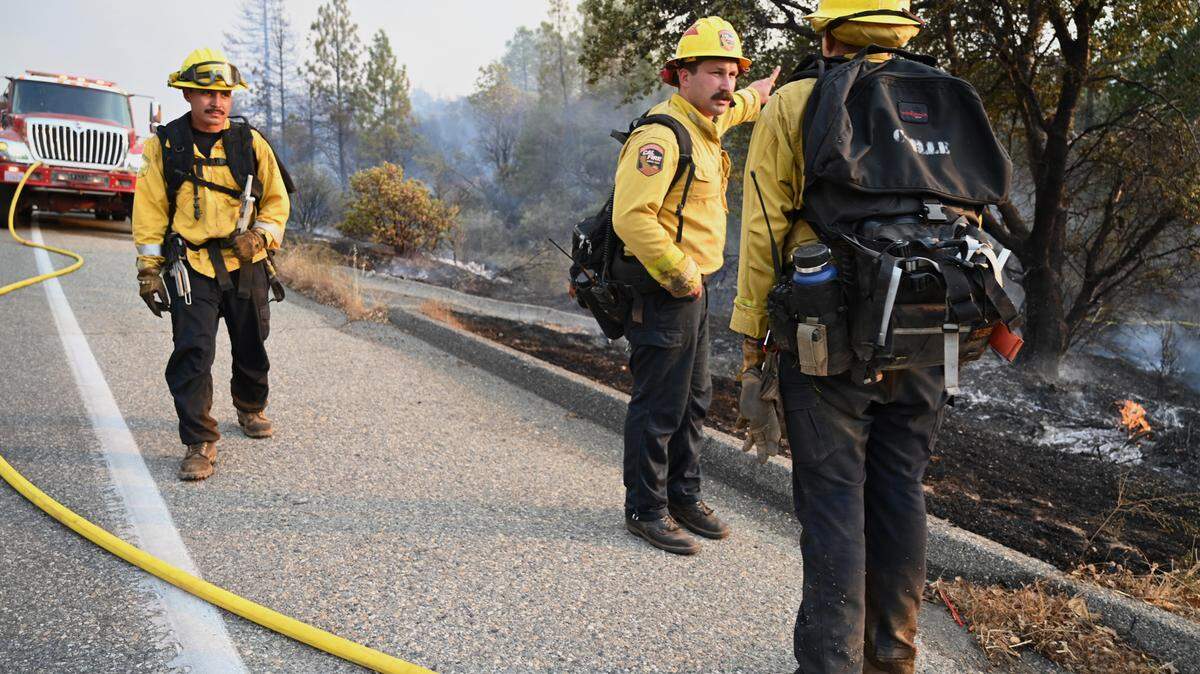 Firefighters stand along Road 225 as the Fork Fire burns near North Fork on Wednesday, Sept. 7, 2022.