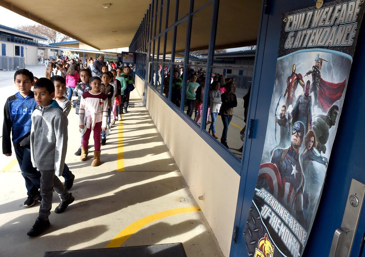 Brletic Elementary School students head back to class, past a poster encouraging superhero attendance, part of a campaign to boost attendance in Parlier schools.