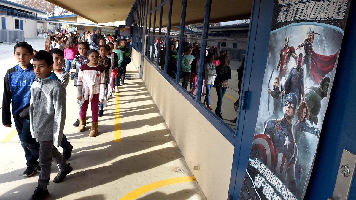 Brletic Elementary School students head back to class, past a poster encouraging superhero attendance, part of a 2020 campaign to boost attendance in Parlier schools.