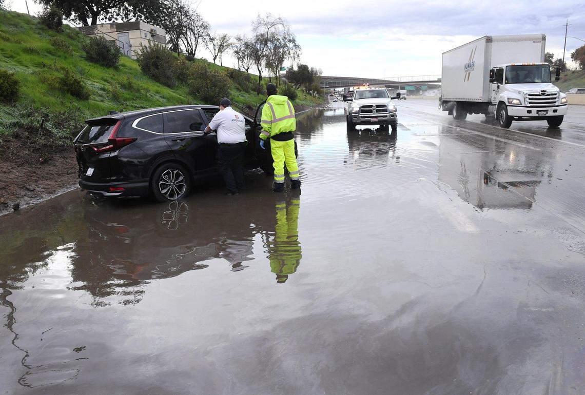 Emergency personnel attend to the driver of a black Honda SUV as southbound 41 traffic backs up merging with southbound 99 near Church Avenue in a flooded portion of the freeway Wednesday, March 10, 2021 in Fresno.