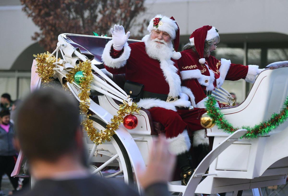 Santa Claus and Mrs. Claus wave from a sleigh perched on a trailer during the Downtown Christmas Parade in Fresno in 2021.