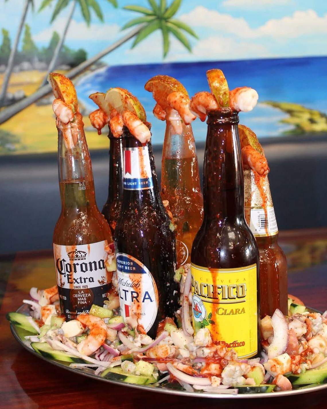 Some of their alcoholic drinks come at Mariscos El Barba Negra come in a bright, orange-reddish color, like the micheladas, the cervezas preparada. and a bottle of Corona drizzled with red chamoy with a shrimp on top.