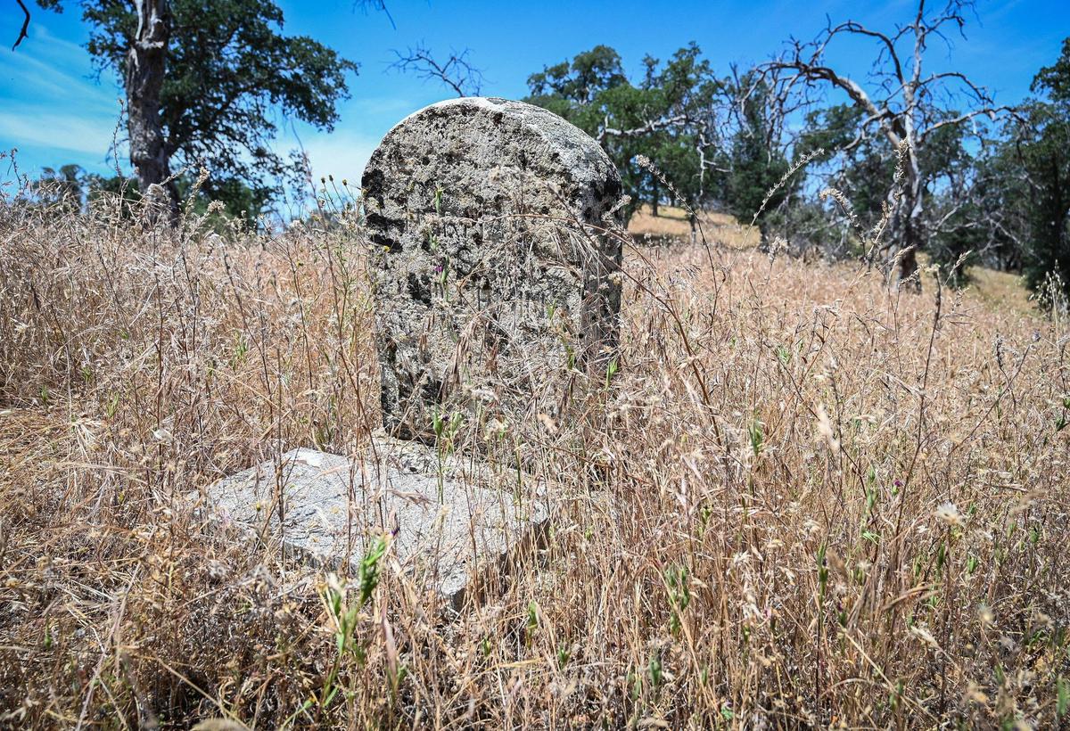 A lichen-covered headstone emerges from the dry grassland in an old Gold Rush era cemetery on the Wright Ranch off Road 600 in Madera County on Wednesday, May 27, 2022. The Wright Ranch was recently acquired as a conservation easement by the Sierra Foothill Conservancy.