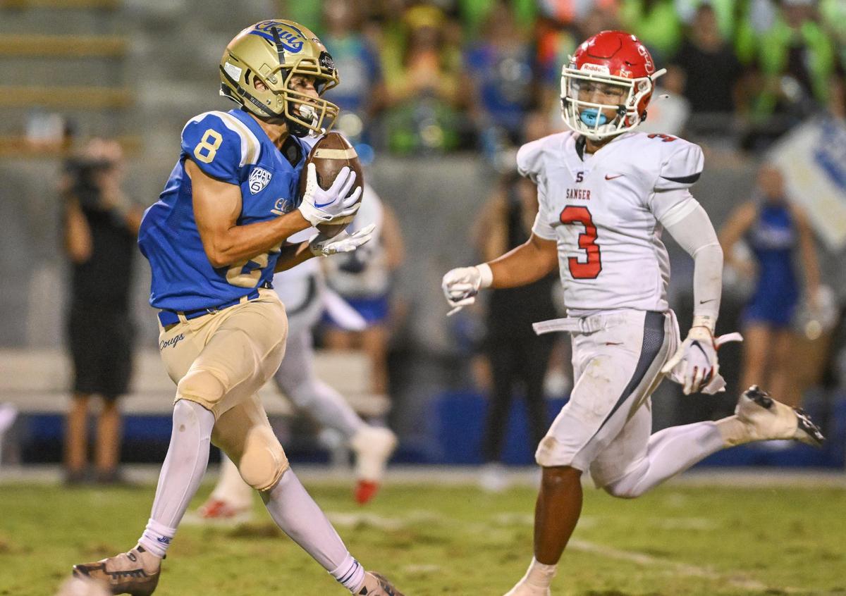 Clovis’ Tyler Marquez, left, turns to make a grab on the ball in front of Sanger’s Jaden Chanthalangsy during their game at Lamonica Stadium in Clovis on Friday, Aug. 25, 2023.