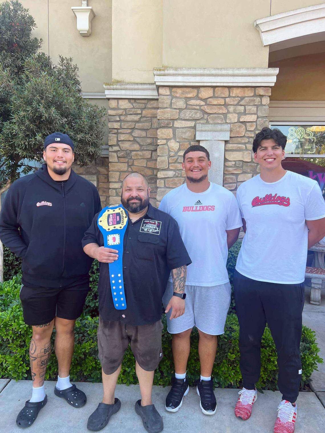 Jonathan Carbajal poses with his Meat Market Mania title belt with the Fresno State Bulldogs’ offensive linemen Julian Polendo, on the left, Jacob Spomer, to the right of Carbajal, and Hayden Pulis, on the far right. The three football players were celebrity judges during the competition this year.