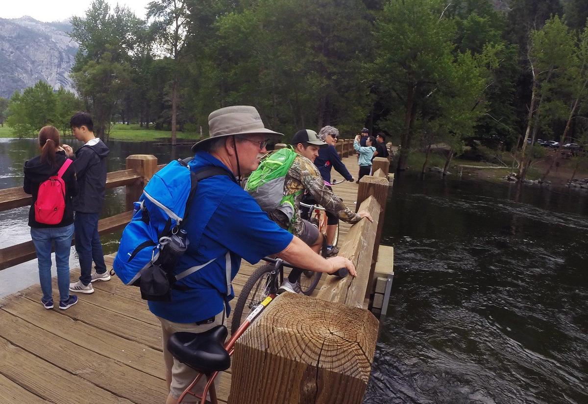 Tourists riding rented bikes cross the Merced River on Swinging Bridge in Yosemite Valley Tuesday, June 4, 2019 in Yosemite National Park.