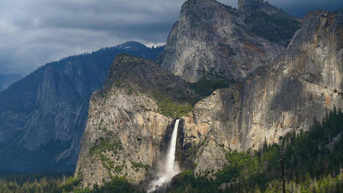 Bridalveil Fall gleams in the late afternoon sunlight as clouds form overhead in Yosemite Valley on Tuesday, June 13, 2023.