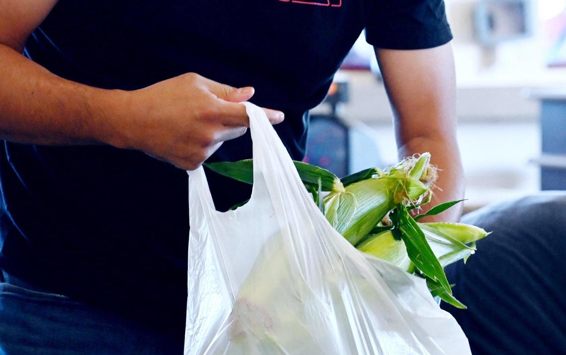 A customer bags his own corn on the first day Rue and Gwen Gibson Farm Market began selling the popular seasonal sweet yellow and white corn. Photographed Monday, May 30, 2022 in Fresno.