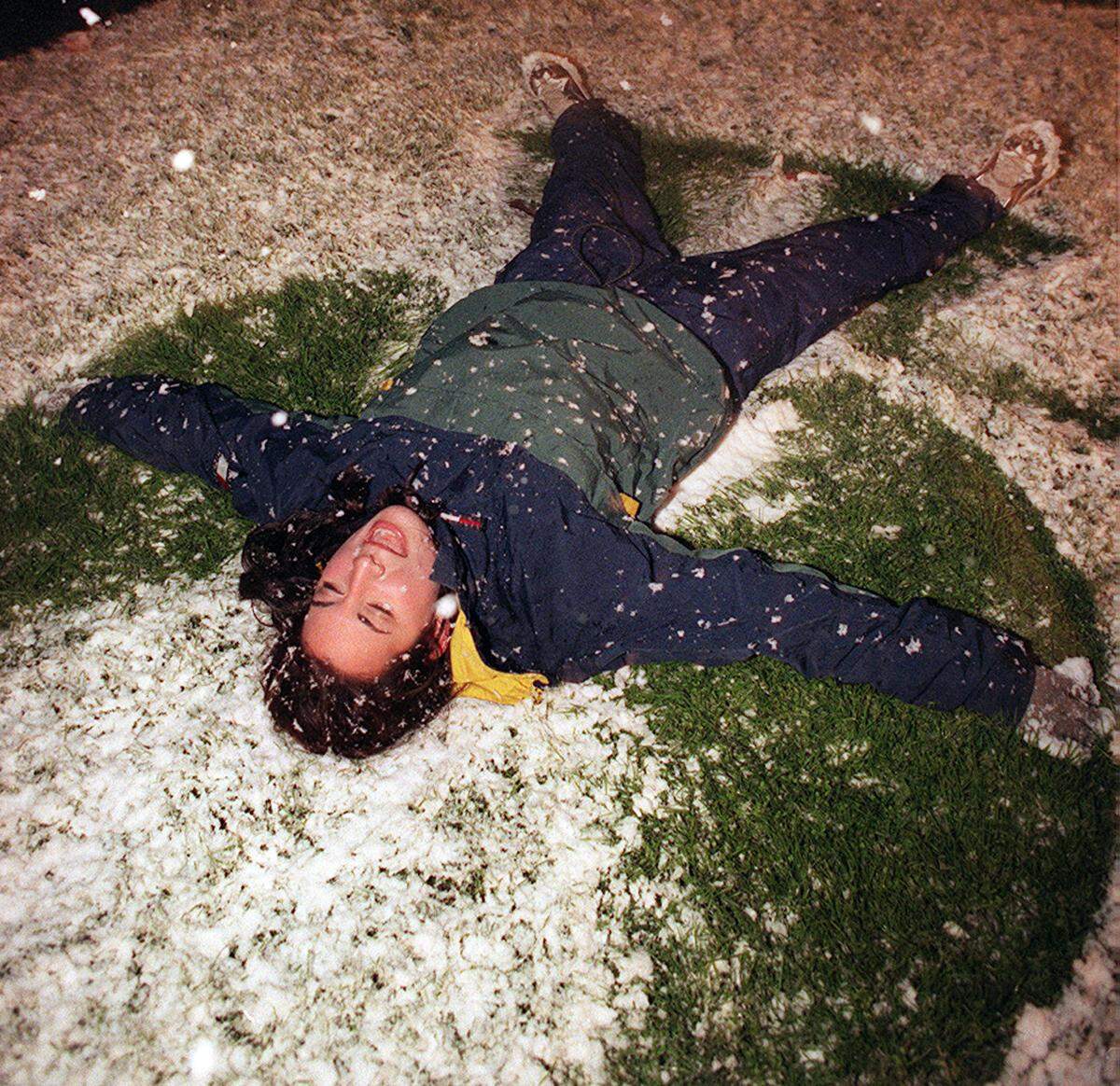 Natalie Niswander makes an angel in the snow along Huntington Boulevard on Sunday night, Dec. 20, 1998, in Fresno.