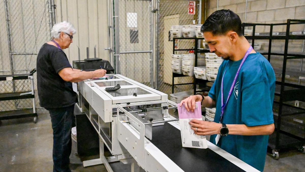 Elections office workers Cheryl Chappell and Jesus Diaz process ballots dropped off at county ballot boxes through a bar code scanner at the Fresno County Elections Department warehouse in Fresno on Monday, June 6, 2022.