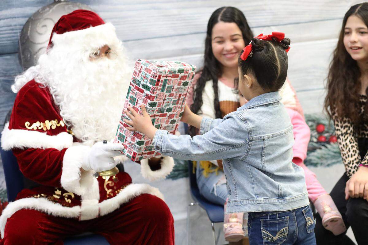 Kindergartener Damaris Ayala, 5, receives a present from Santa during the 2023 Migrant Family Christmas event that took place at Firebaugh High School library on Dec. 13.