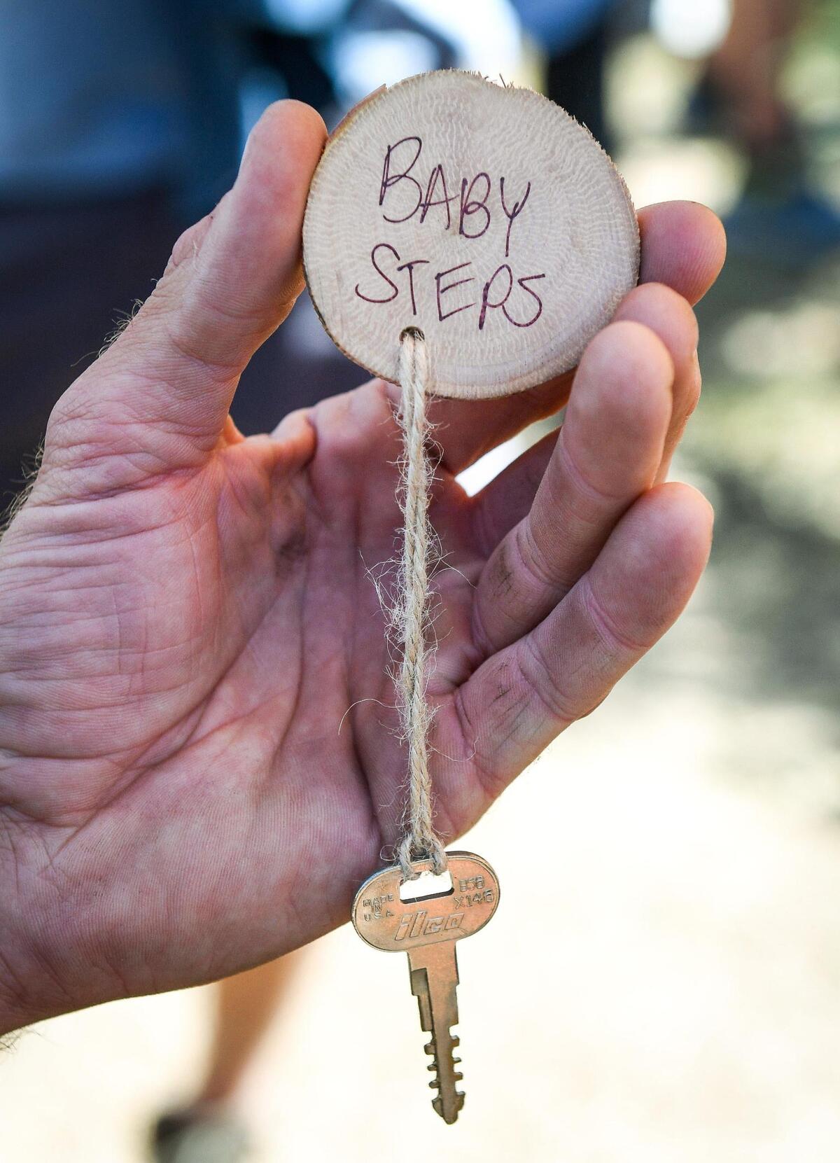 Joe Armas holds up the key he picked out from the survivors tree, meant to be a symbolic gesture to move past the pain of the devastation, and work toward healing during the Creek Fire Recovery Collaborative’s One Year Stronger event in Shaver Lake on Saturday, Sept. 4, 2021. Arias wrote “baby steps” on the circular cutting of a tree limb on the key as encouragement to keep moving forward.
