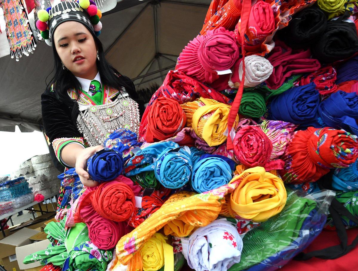 Macy Thao, 19, of Rocklin, California, shops for colorful skirts during opening day of the Hmong New Year celebration at the Fresno Fairgrounds, Thursday morning, December 30, 2021.