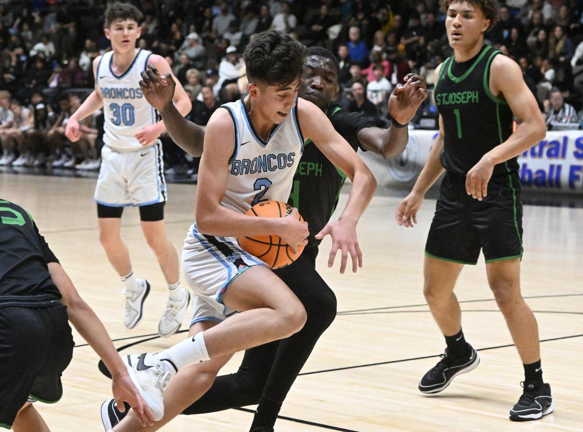 Clovis North’s Elias Gish, foreground, drives past St. Joseph’s Abdul Bare, background, in the Central Section Division I basketball championship Saturday, Feb. 24, 2024 at Selland Arena in Fresno.