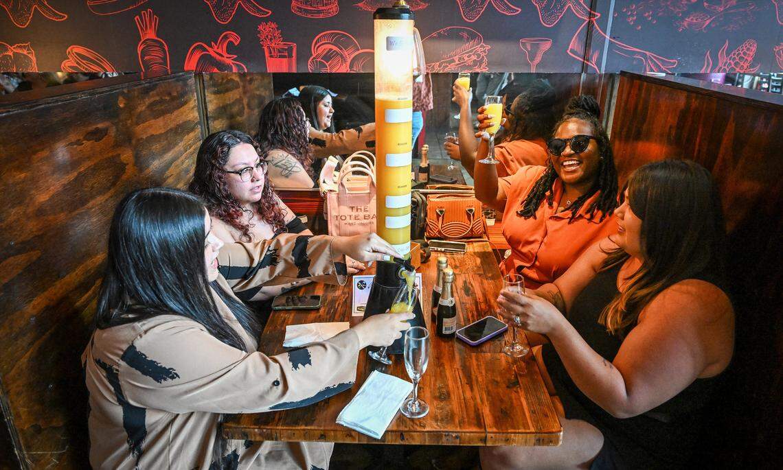 Friends tap off their glasses from a mimosa tower while celebrating together at Kocky's Bar & Grill in downtown Fresno during their Butta Brunch on Sunday morning, Aug. 10, 2025.