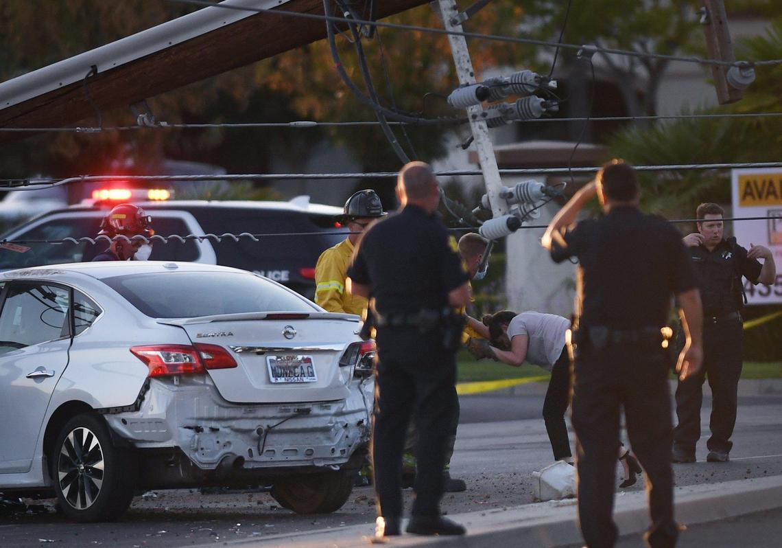A woman involved in a car crash who was trapped in her vehicle underneath a power pole with live wires is helped away from the scene by a firefighter Wednesday, August 4, 2021 in Fresno. She was helped out of the vehicle by rescue personnel after PG&E turned the power off.