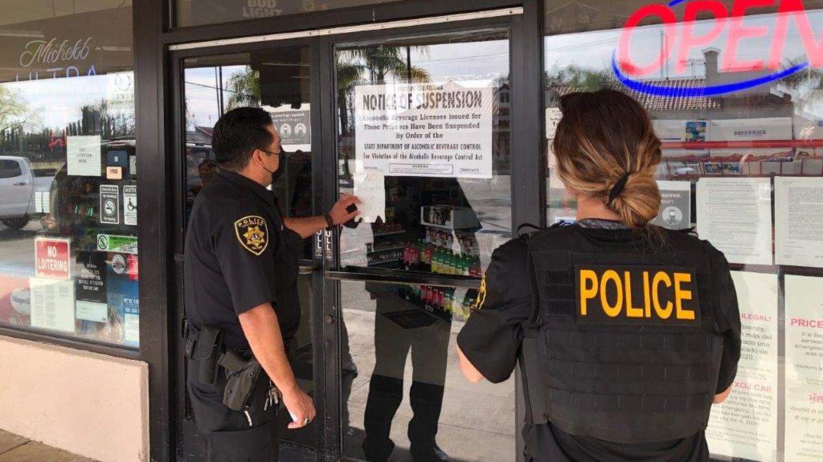 Agents with The California Department of Alcoholic Beverage Control post a notice of suspension outside University Deli Liquor in Fresno.