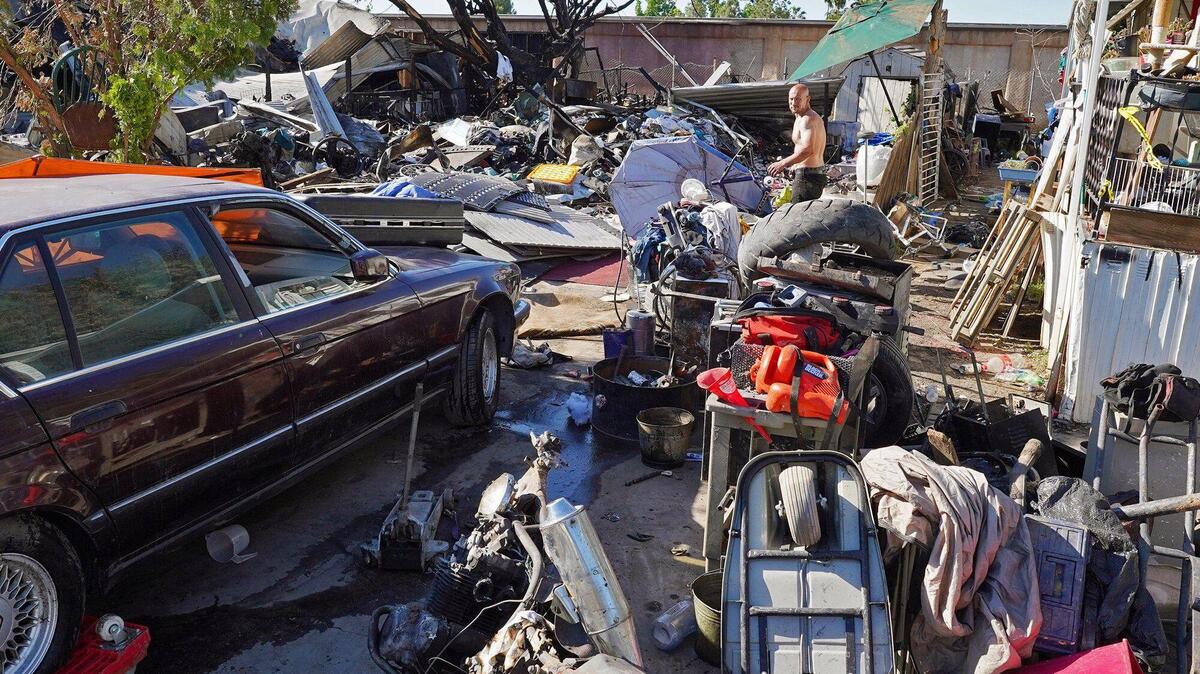 An unidentified man walks through burned items where two lots burned at the Trail’s End Mobile Home Park, leaving one dead Thursday April 29, 2021. Photographed Tuesday May 4, 2021 in Fresno.