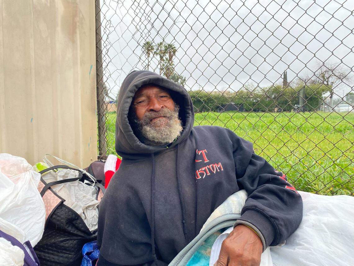 Wickey Two Hands, 77, poses on a rainy Wednesday, March 5, 2025, on the corner where he spent the previous night. He is on pace to be the first unhoused person who will face trial under Fresno’s 6-month-old anti-camping law.