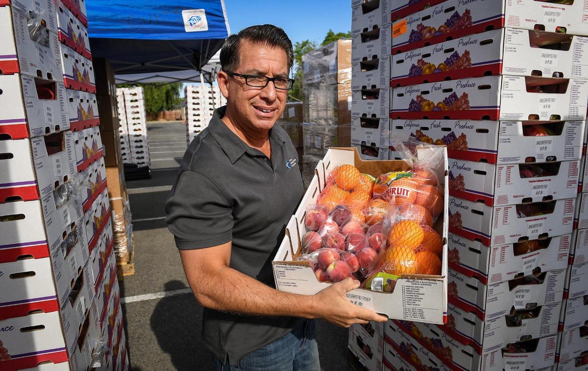 Artie Padilla, executive director of Every Neighborhood Partnership, holds up a box of fruit during a food distribution at Cooper Academy Middle School in Fresno on Friday, June 11, 2020.