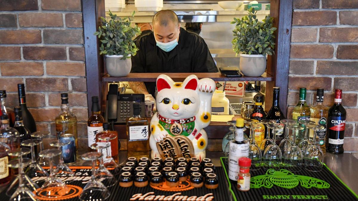 Sushi chef James Satthi is seen through a window from the dining room to the kitchen as he prepares sushi rolls at Banzai, a new Japanese cuisine restaurant in the Tower District on Friday, March 26, 2021.
