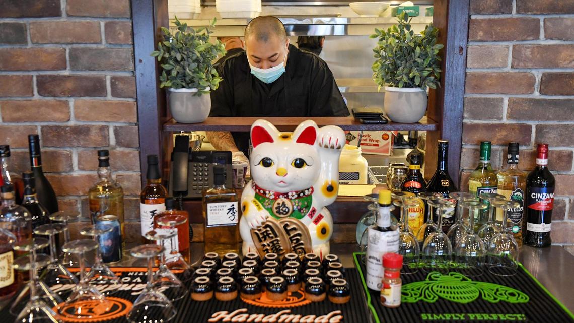 Sushi chef James Satthi is seen through a window from the dining room to the kitchen as he prepares sushi rolls at Banzai, a new Japanese cuisine restaurant in the Tower District on Friday, March 26, 2021.