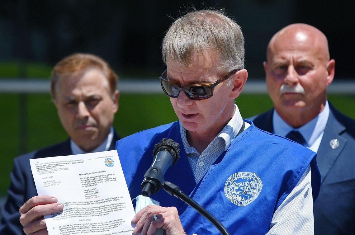 Kyle Krause, Deputy Director of Codes and Standards for the State of California, center, holds up a notice of abatement for Trails Ends Mobile Home Parkm with Fresno Mayor Jerry Dyer to the right, and councilperson Garry Bredefield to the left, at a press conference following after the previous night’s fire at Trails End Mobile Home Park Thursday, June 10, 2021 at City Hall in Fresno.