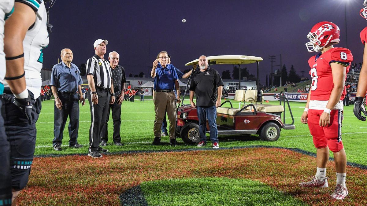Recent NFL Hall of Fame inductee Tom Flores, center, makes the coin toss before the start of the Sanger Apaches football game against Kennedy at Tom Flores Stadium in Sanger on Friday, Sept. 17, 2021.