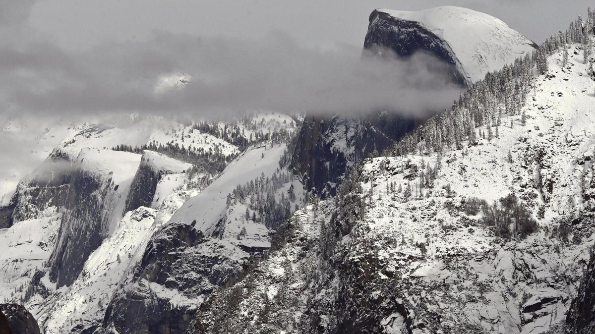 A cloud partially obscures Half Dome, top right, with Cloud’s Rest to the left as the higher elevations around Yosemite Valley still show snow from its last snowfall, photographed Friday, Feb 9, 2024 in Yosemite National Park.