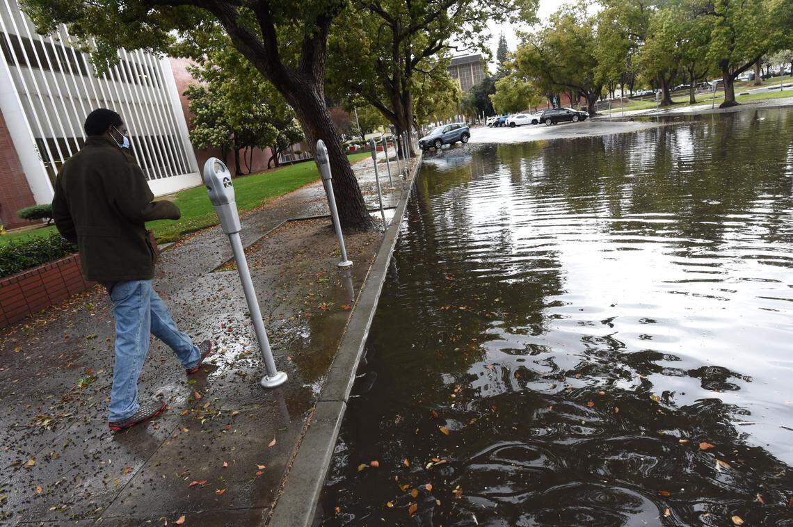 A man walks past a flooded section of Mariposa Street in downtown Fresno at the end of Wednesday’s storm.