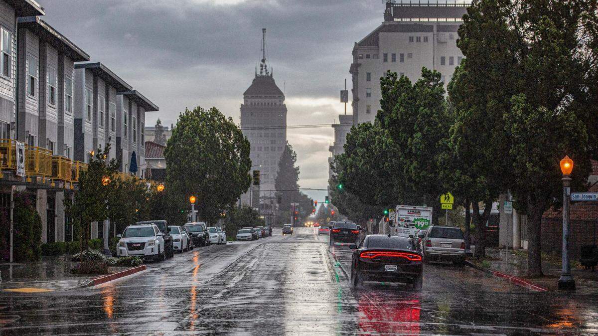 Cars driving into downtown as a late-season storm front brings rain to Fresno Monday evening on March 28, 2022.