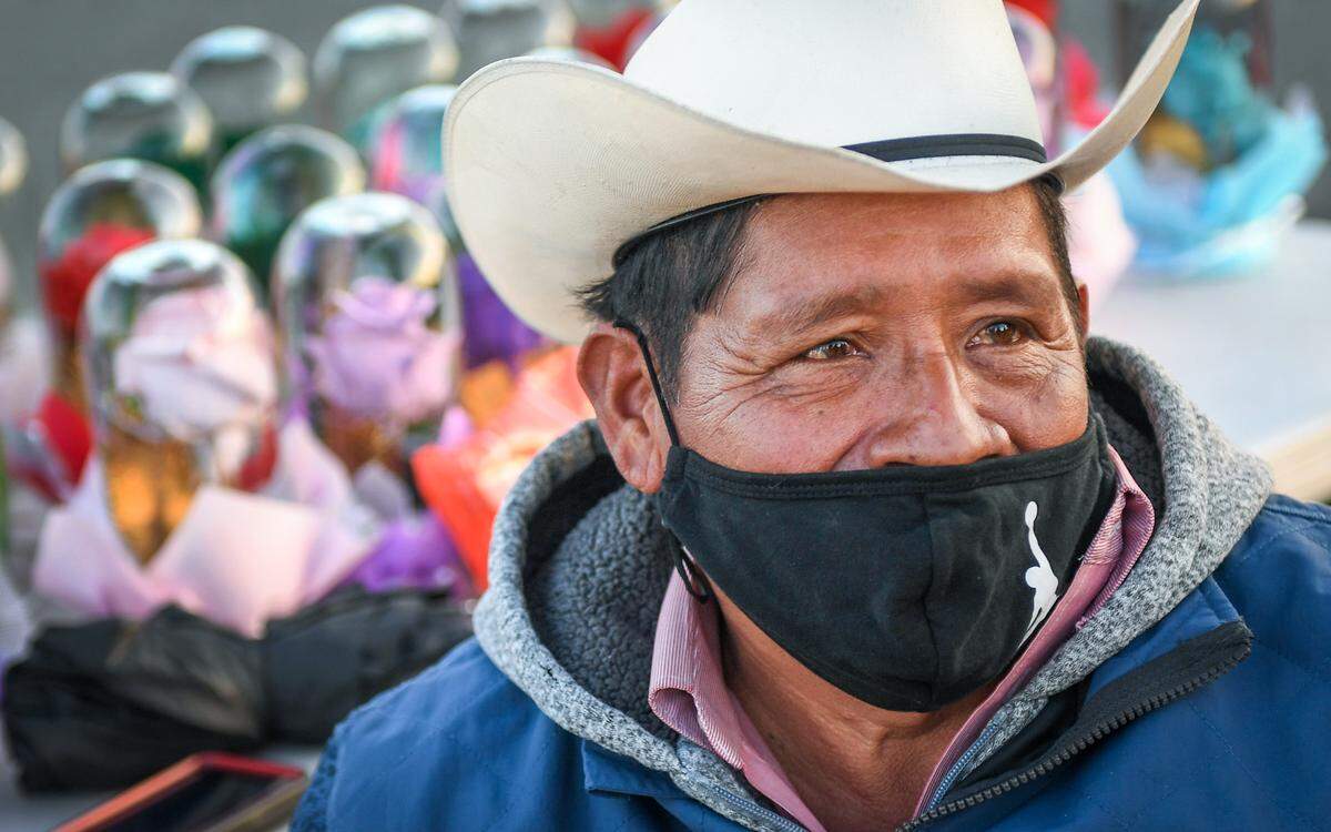 Guillermo Lozano smiles behind his COVID-19 mask while sitting in a chair on the side of the road in rural Madera County, where he sells flowers and gifts on Friday, Dec. 18, 2020. A GoFundMe account has been started to help Lozano purchase a new prosthetic leg.