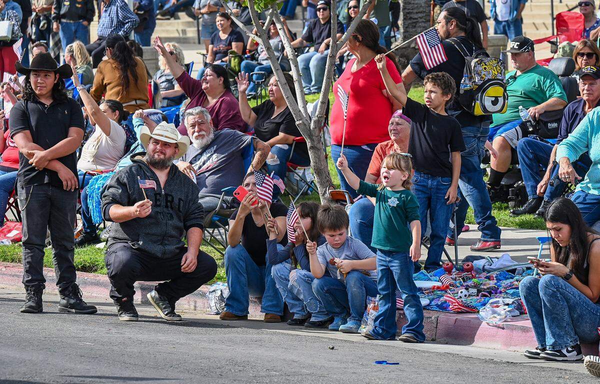 Parade-watchers wave flags during the Central Valley Veterans Day Parade in downtown Fresno on Tuesday, Nov. 11, 2025. 