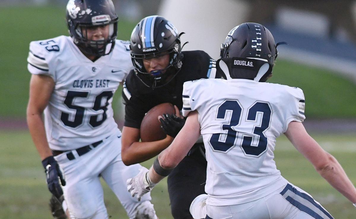Clovis North quarterback Mario Costa, center, cuts back past Clovis East’s Jax Koontz, right, Friday, Sept. 30, 2022 in Clovis.