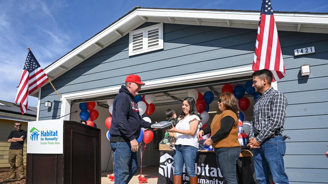 Rick O’Daniel, construction manager with Habitat for Humanity Greater Fresno Area presents the Munoz family, from left, Daniela, her mother, Mary Elizabeth Garcia and husband David with their son Mateo, with a photo album of photos showing work on their new home in Clovis on Friday, Feb. 18, 2022.