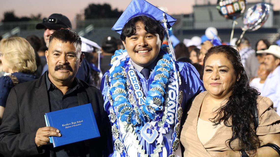 Jordan López, estudiante de último año de Caruthers High School, con sus padres después de su ceremonia de graduación, el viernes 2 de junio, en el estadio de la preparatoria.