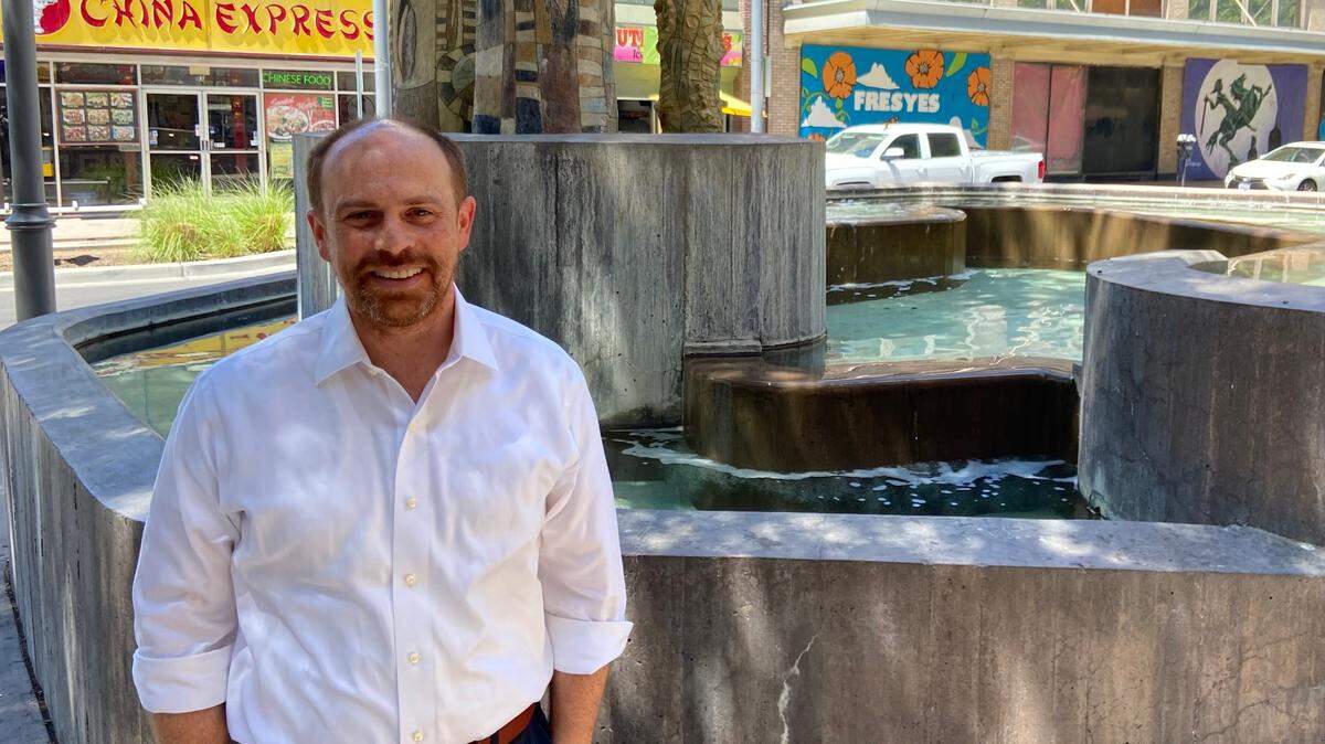 Ellliott Balch, president and CEO of the Downtown Fresno Partnership, a business improvement district, poses next to one of the four “Pipes” sculptures and fountains located along Fulton Street on July 11, 2023.