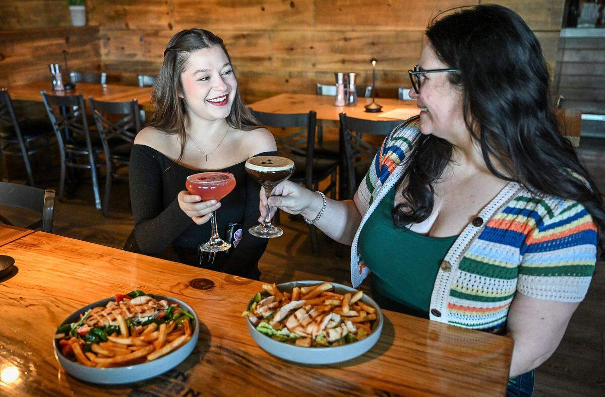 Ten Tavern server Sam Hugues and owner Vanessa Medlock toast to their “girl dinner” salads, fries and cocktails at the establishment's Willow and Nees location in Clovis on Tuesday, May 19, 2026. Ten Tavern is one of several local restaurants that offer a “girl dinner” option on their menu for a limited time.