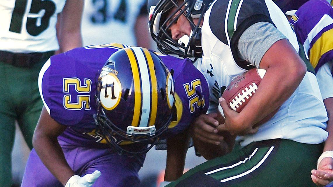 Reedley High’s Zach Lampa, center, takes a hit but spins free from Fresno High’s Terry Robinson, left. in the first of a double header Friday, April 2, 2021 in Fresno. Reedley took the win 34-7.