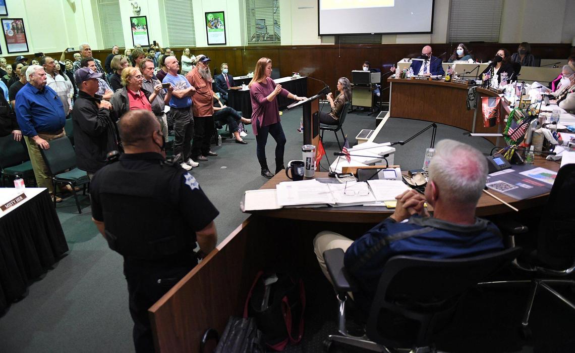 The majority of the audience, an estimated 60 people, left, take turns standing in support of speakers speaking out against vaccine and mask mandates at the Fresno Unified School Board meeting Wednesday night, Feb. 16, 2022 in Fresno.